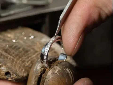 A jeweller at the bench, working on a diamond band with a hand tool