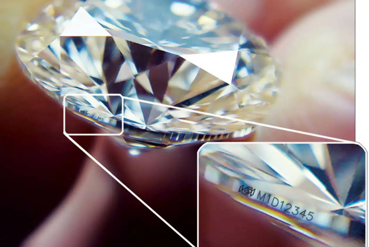 Close-up of a diamond with an enlarged inset showing a laser inscription on its girdle.