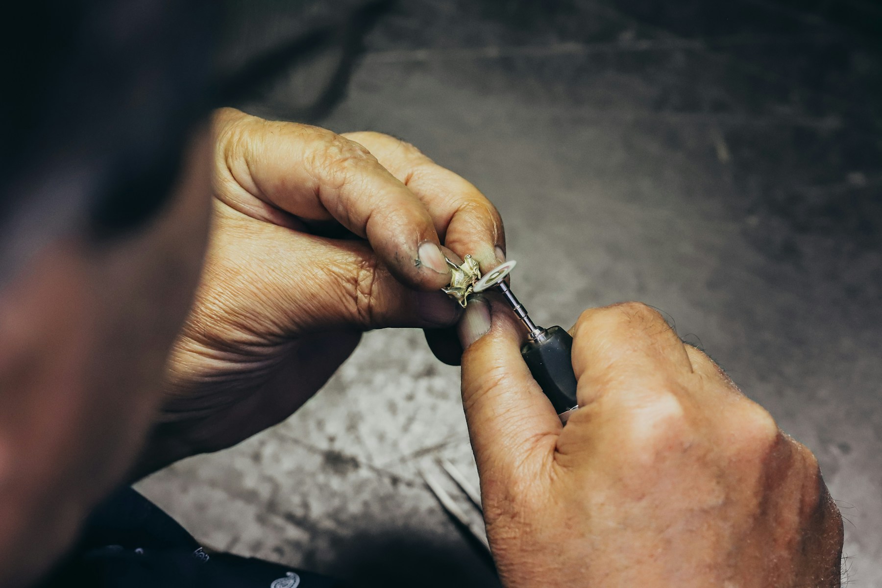 A jeweller using a rotary tool to finish a small jewellery component.