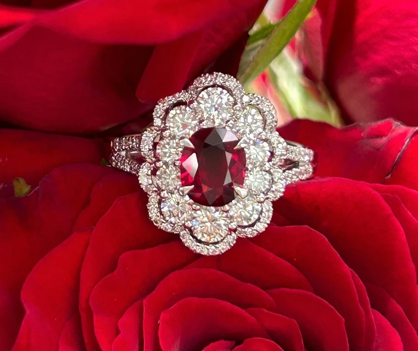 Red-centred ring with a scalloped halo and split shoulders, resting on rose petals.