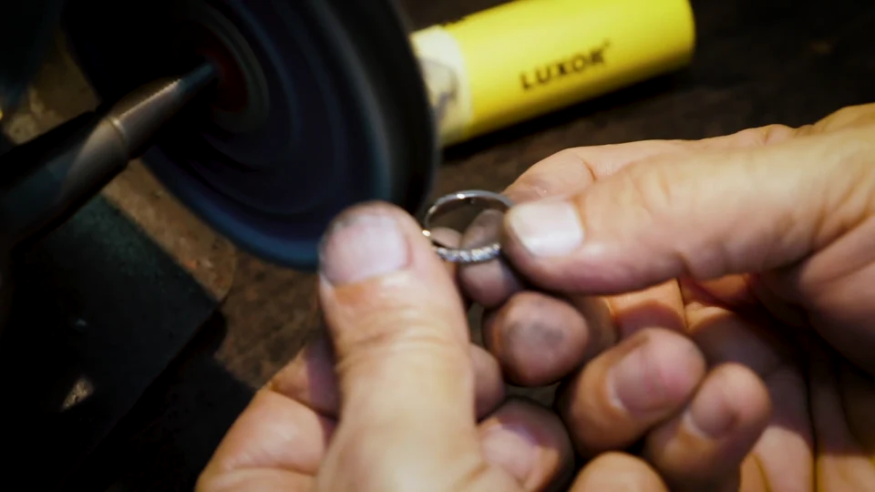 A jeweller carefully polishing a ring at the workshop