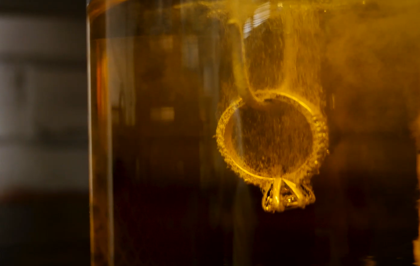 A ring suspended in a rhodium-plating bath, surrounded by small bubbles