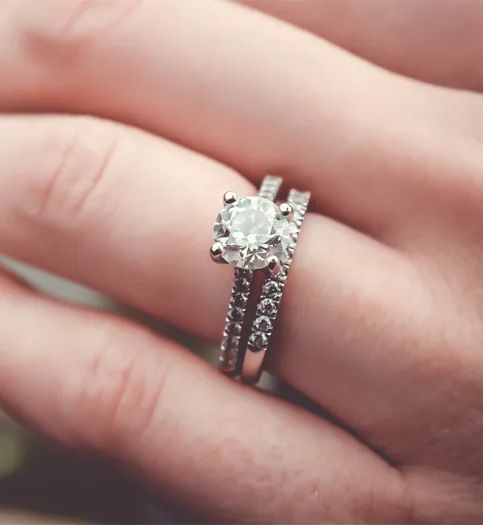 A solitaire engagement ring and diamond wedding band worn together