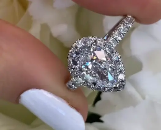 Pear shaped diamond ring held between fingers